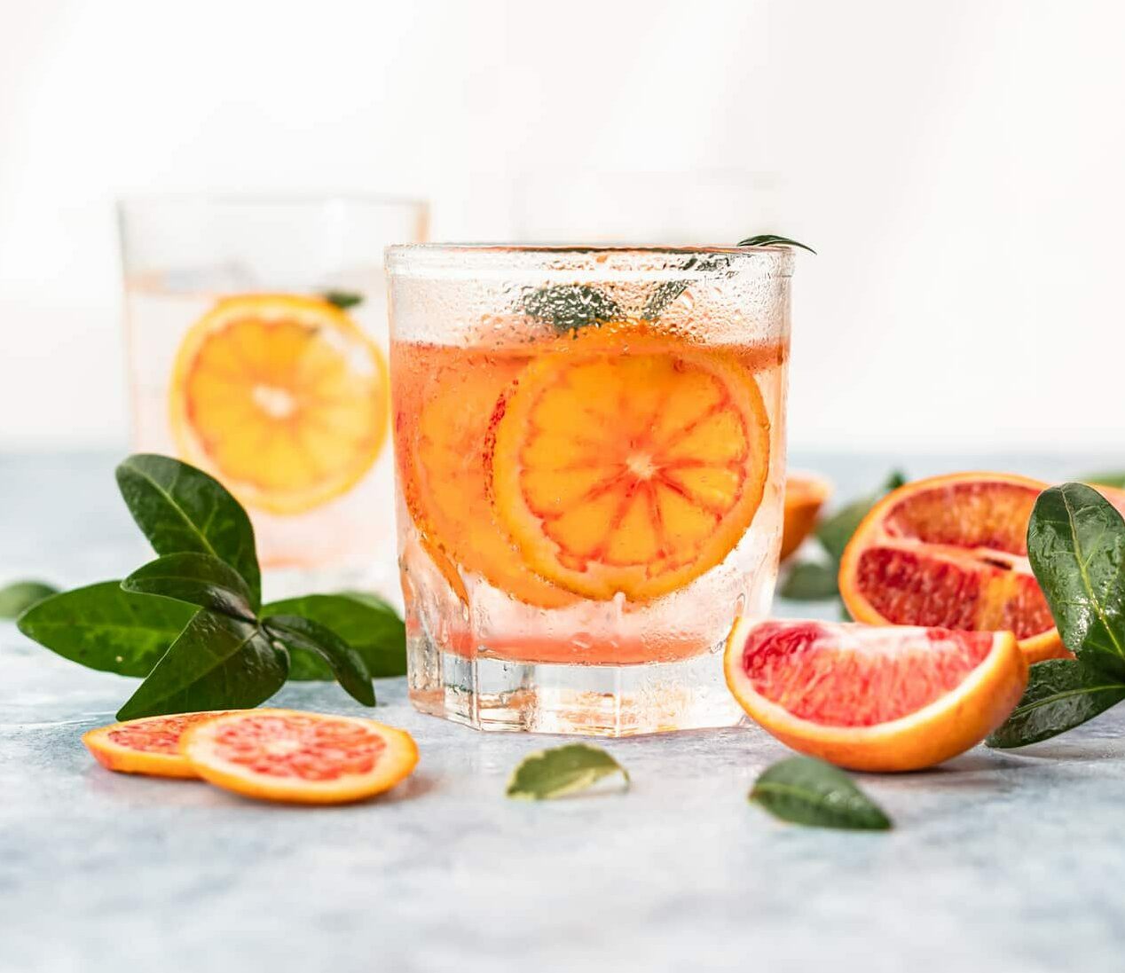 Hard seltzer cocktail with blood orange. Cocktail or lemonade with fresh citrus. Refreshing drinks, low alcohol mocktails. Party concept. Shadow and sunlight.